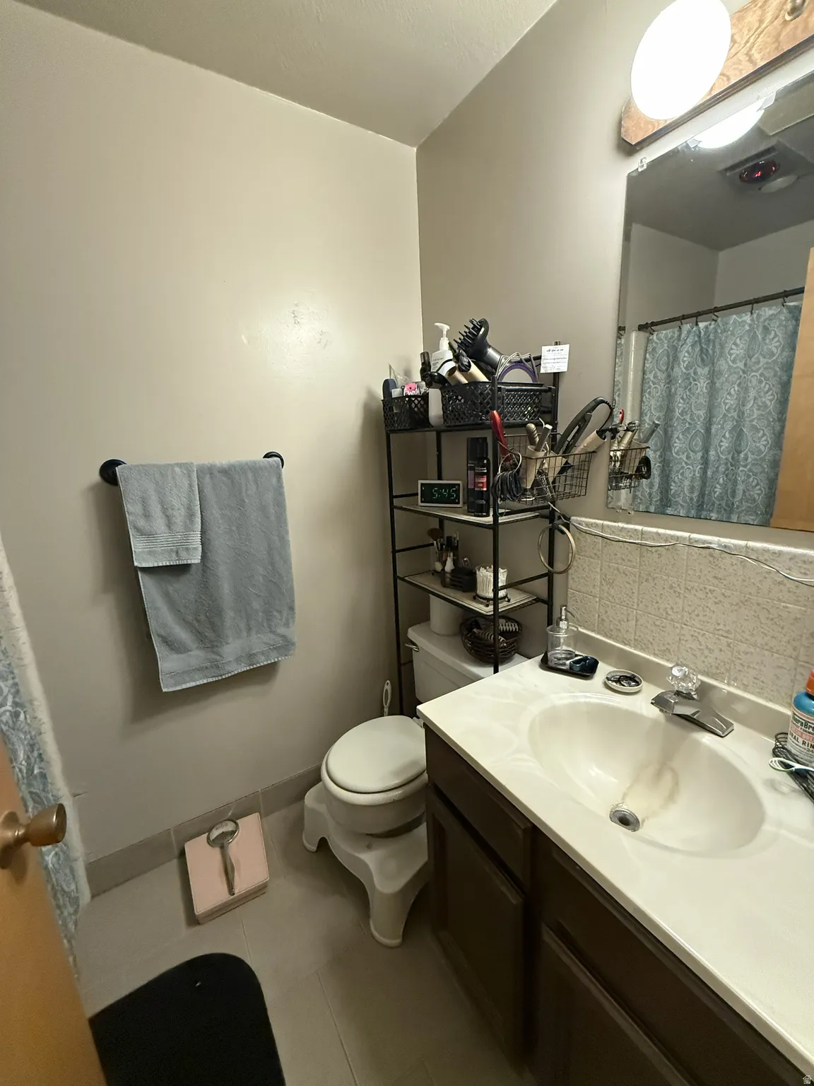 Bathroom featuring a vanity with an integrated sink, a large wall-mounted mirror, and tile flooring