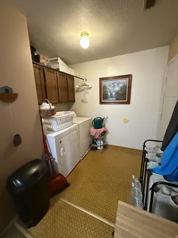 Laundry area featuring upper cabinetry, a hanging rod, and textured flooring
