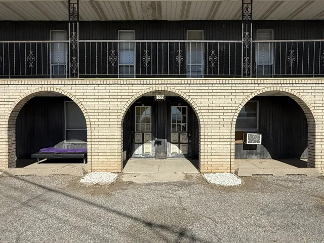 Two-story exterior featuring a light-colored brick archway facade