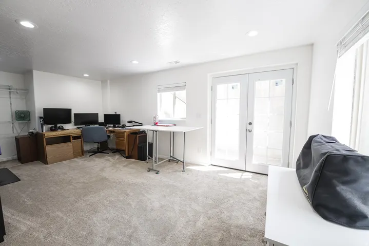 Light-filled room featuring double glass-paneled doors, recessed lighting, carpet flooring, and a window with blinds