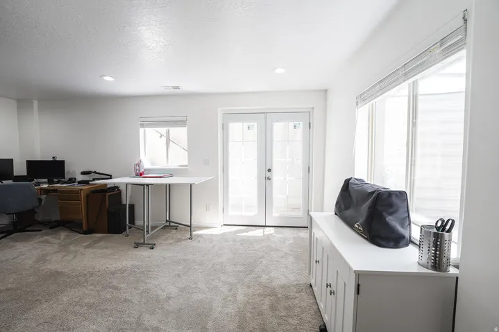 Carpeted room featuring white walls, recessed lighting, double French doors, and an additional window