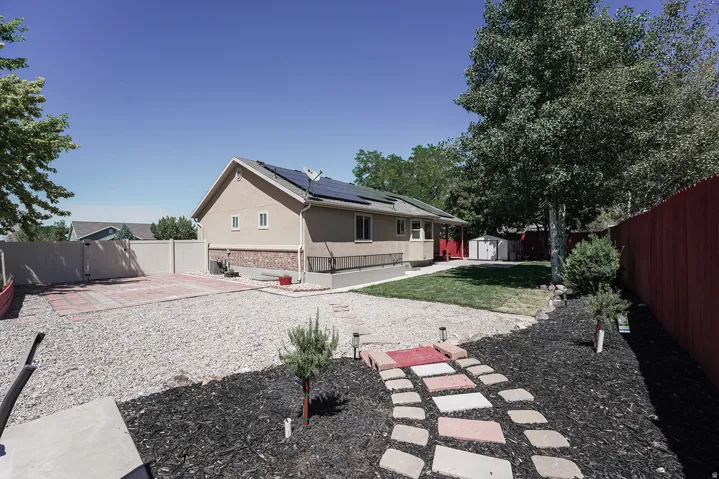 Expansive backyard featuring a gravel patio, paver stone walkway, and mature trees