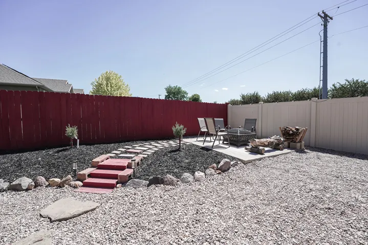 Expansive outdoor space featuring a red privacy fence and a dedicated patio area
