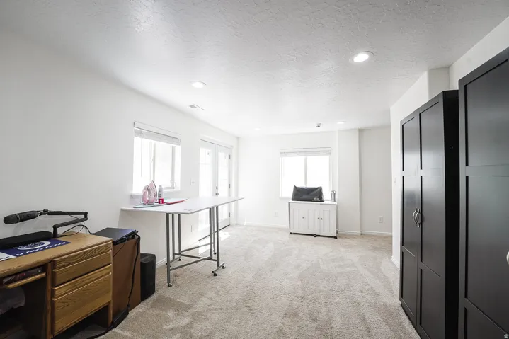 Carpeted room with recessed lighting, multiple windows, French doors, and built-in black cabinetry
