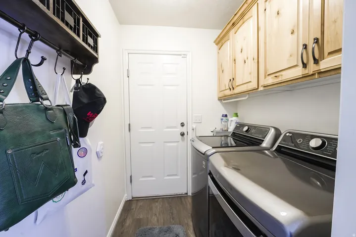 Dedicated laundry area featuring wood-finish flooring and a paneled entry door