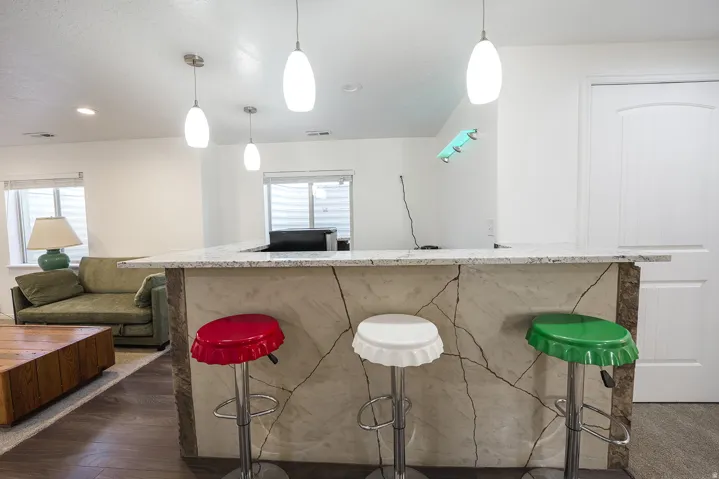 Entertainment bar featuring a light-toned stone-finish countertop, decorative stone-finish base, and pendant lighting