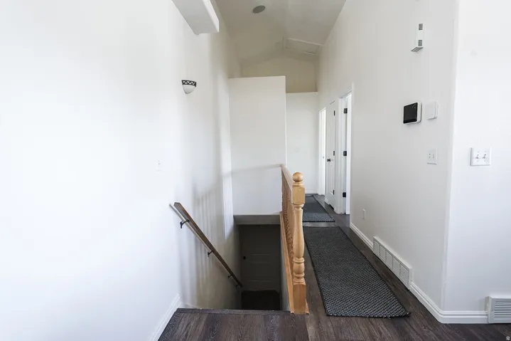 Upper level hallway featuring wood-finish flooring, white baseboards, and bright white walls