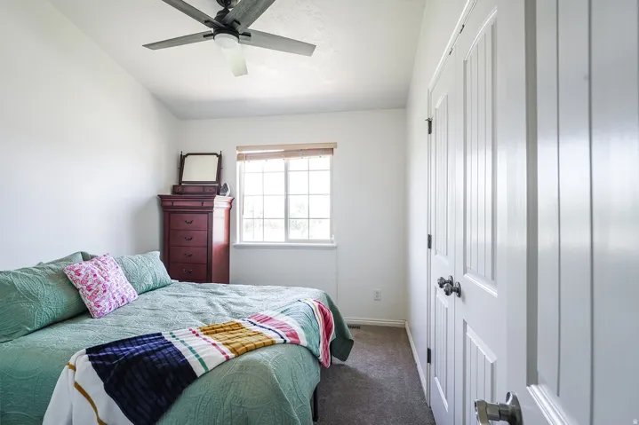 Bright room featuring a window with natural light, a ceiling fan with integrated lighting, wood-finish flooring, and white paneled doors