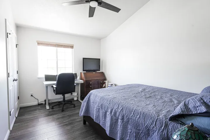 Bedroom featuring wood-finish flooring, a ceiling fan, and a window with blinds
