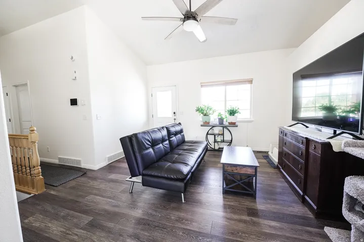 Living area featuring vaulted ceilings, wood-finish flooring, and a ceiling fan
