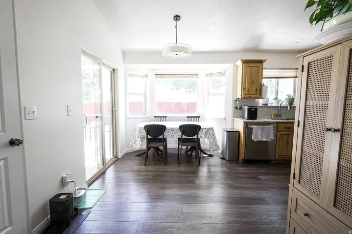 Open-concept dining and kitchen area featuring wood-finish flooring, a bay window with natural light, and sliding glass doors to the exterior