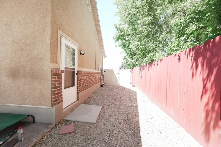 Stucco exterior with brick detailing, a dedicated side entry door, and a gravel pathway