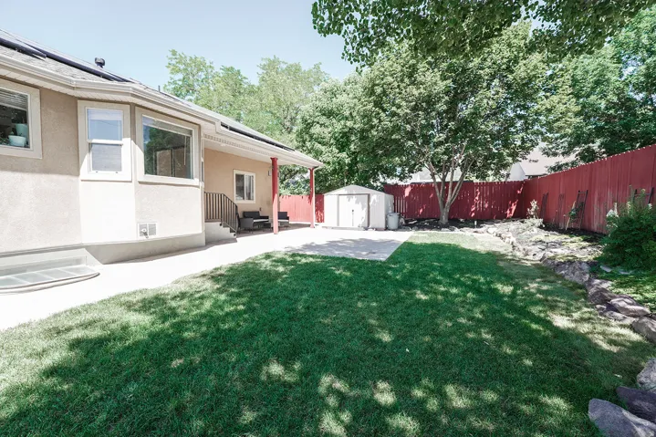 Expansive backyard featuring a manicured lawn, a concrete patio, and mature trees