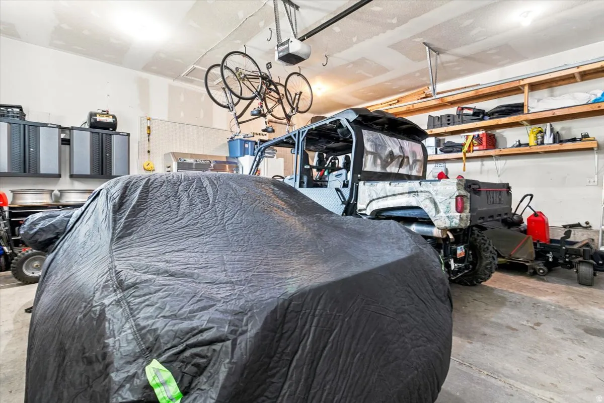 Spacious garage with overhead lighting, built-in wall shelving, cabinet storage, and a concrete floor