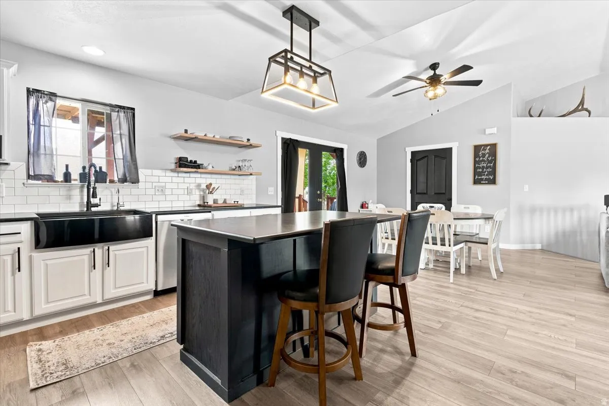 Kitchen featuring a black farmhouse sink, white subway tile backsplash, and light wood-finish flooring