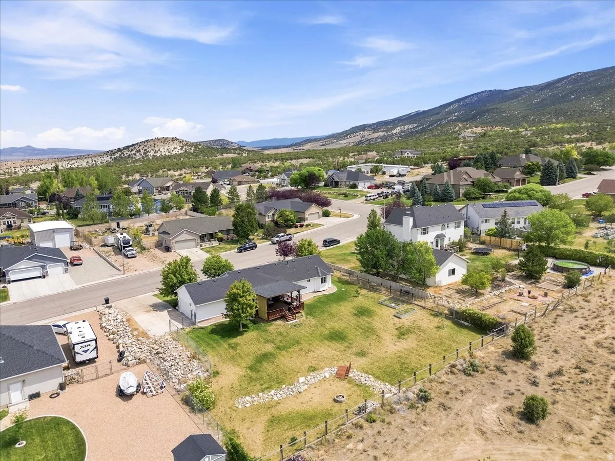 Expansive property featuring a large backyard with a fenced garden area, established trees, and a mountain backdrop