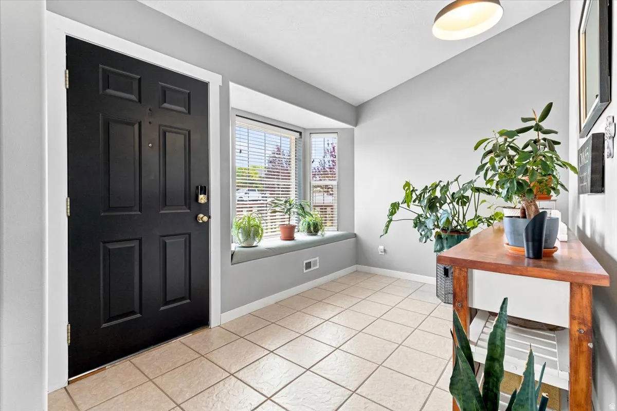 Entryway featuring neutral tile flooring, a dark paneled door with brass hardware, and a bay window with integrated seating