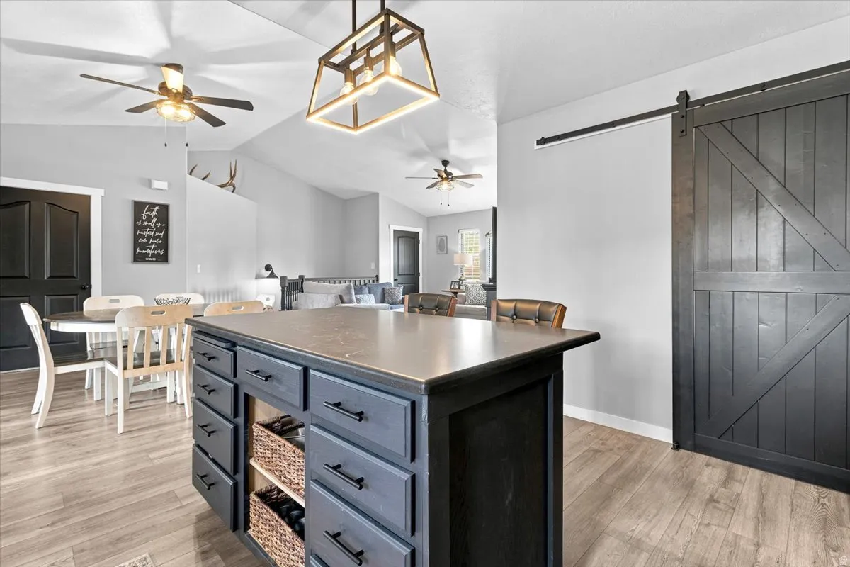 Kitchen island with integrated storage, wood-finish flooring, and a sliding barn door