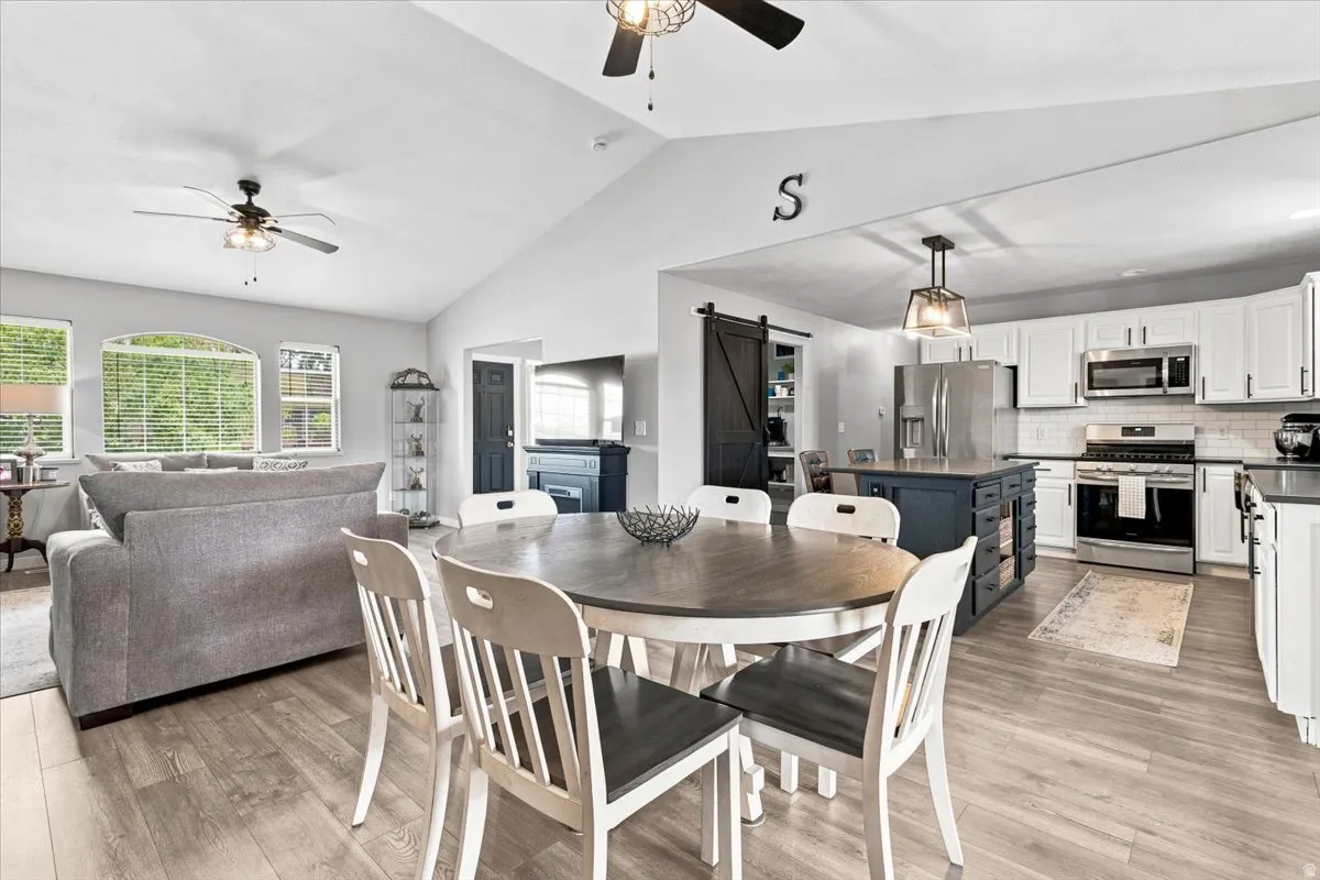 Open-concept interior featuring wood-finish flooring, vaulted ceilings, and a kitchen with stainless steel appliances