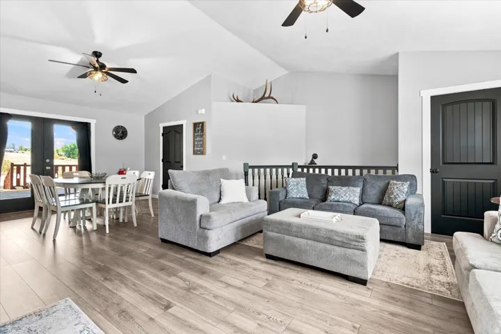 Open-concept living space featuring wood-finish flooring, vaulted ceilings, and ceiling fans