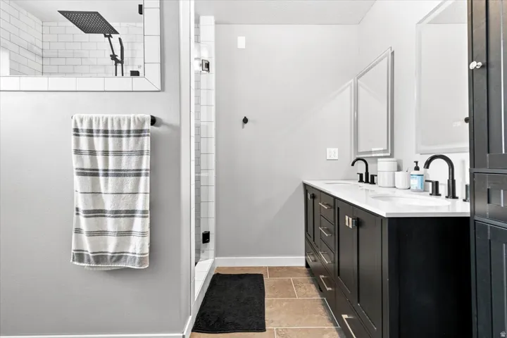 Master bath with double vanity with black cabinetry, white countertops, and LED touchscreen defogger mirrors.