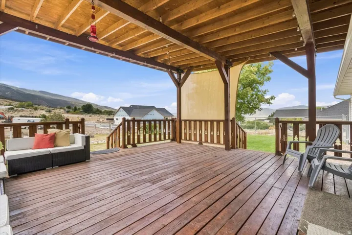 Spacious covered wood-finish deck with exposed beam ceiling, wood railings, and mountain backdrop