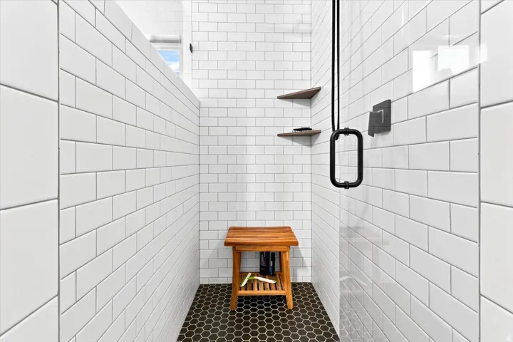Shower with white subway tile walls and black hexagonal floor tile