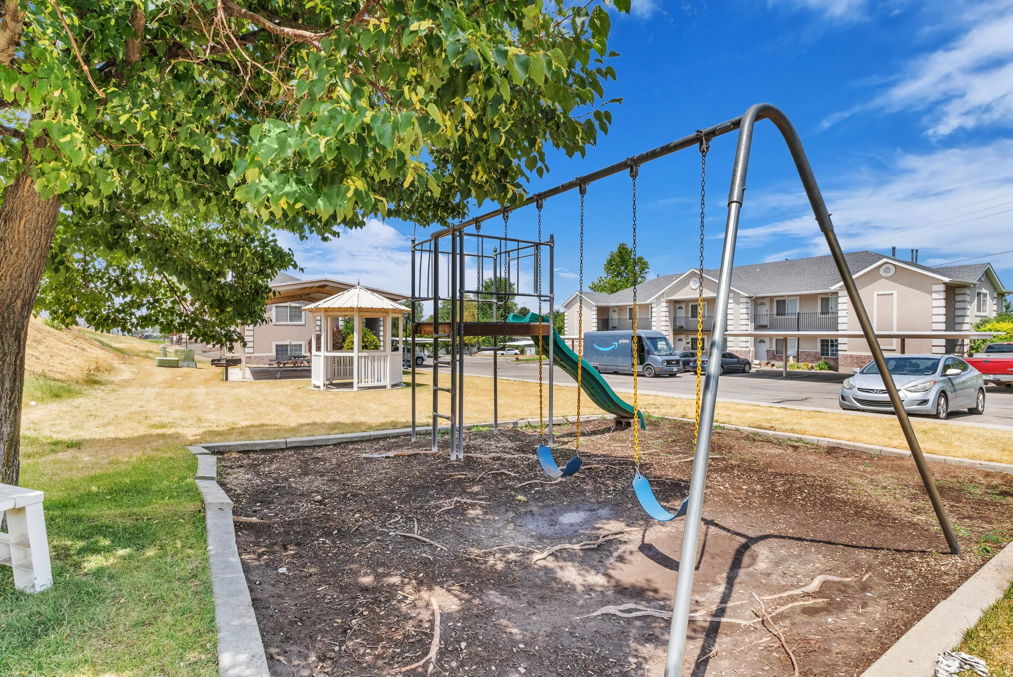 Outdoor recreation area featuring a swing set, slide, and a white gazebo