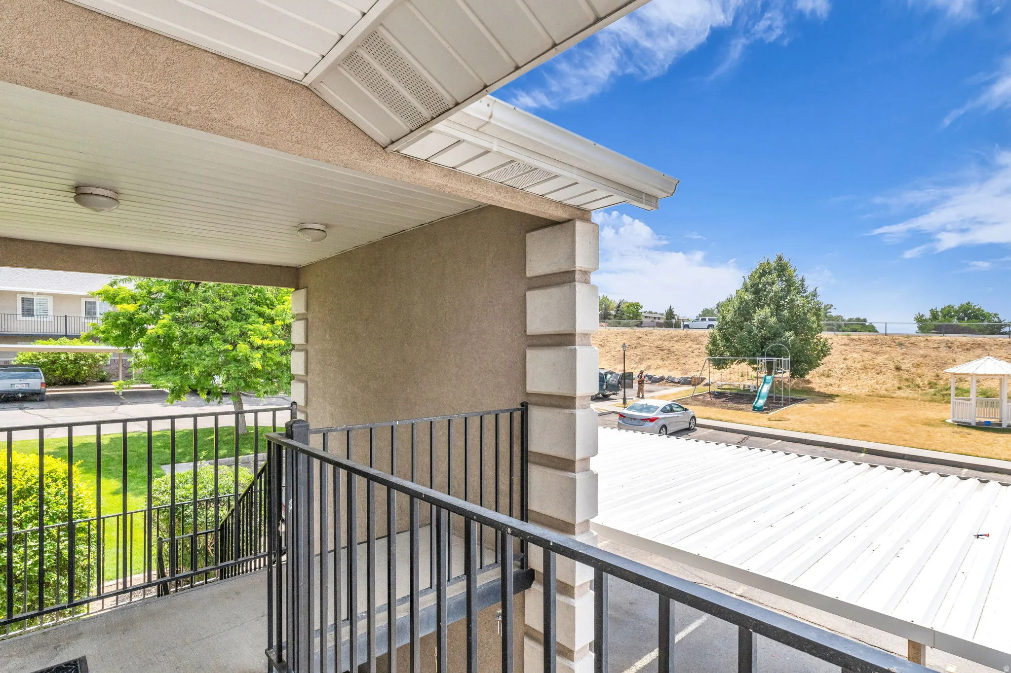Covered exterior walkway with textured stucco walls and white soffit, featuring flush-mounted lighting fixtures