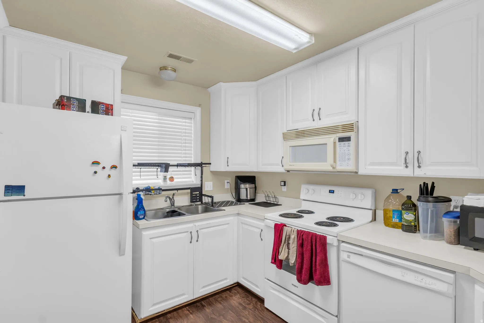Kitchen with white cabinetry, a double basin sink, and wood-finish flooring