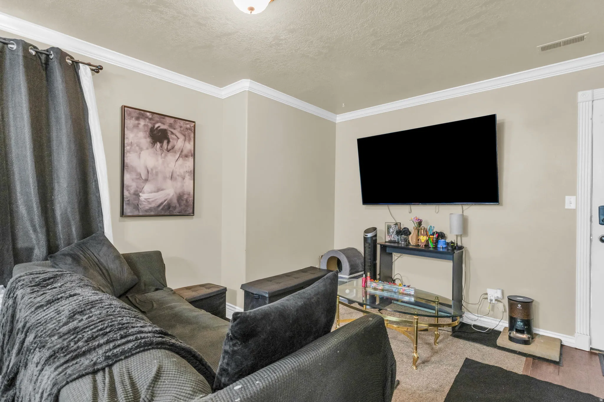 Living area featuring crown molding, neutral wall tones, carpet flooring, and a ceiling-mounted light fixture