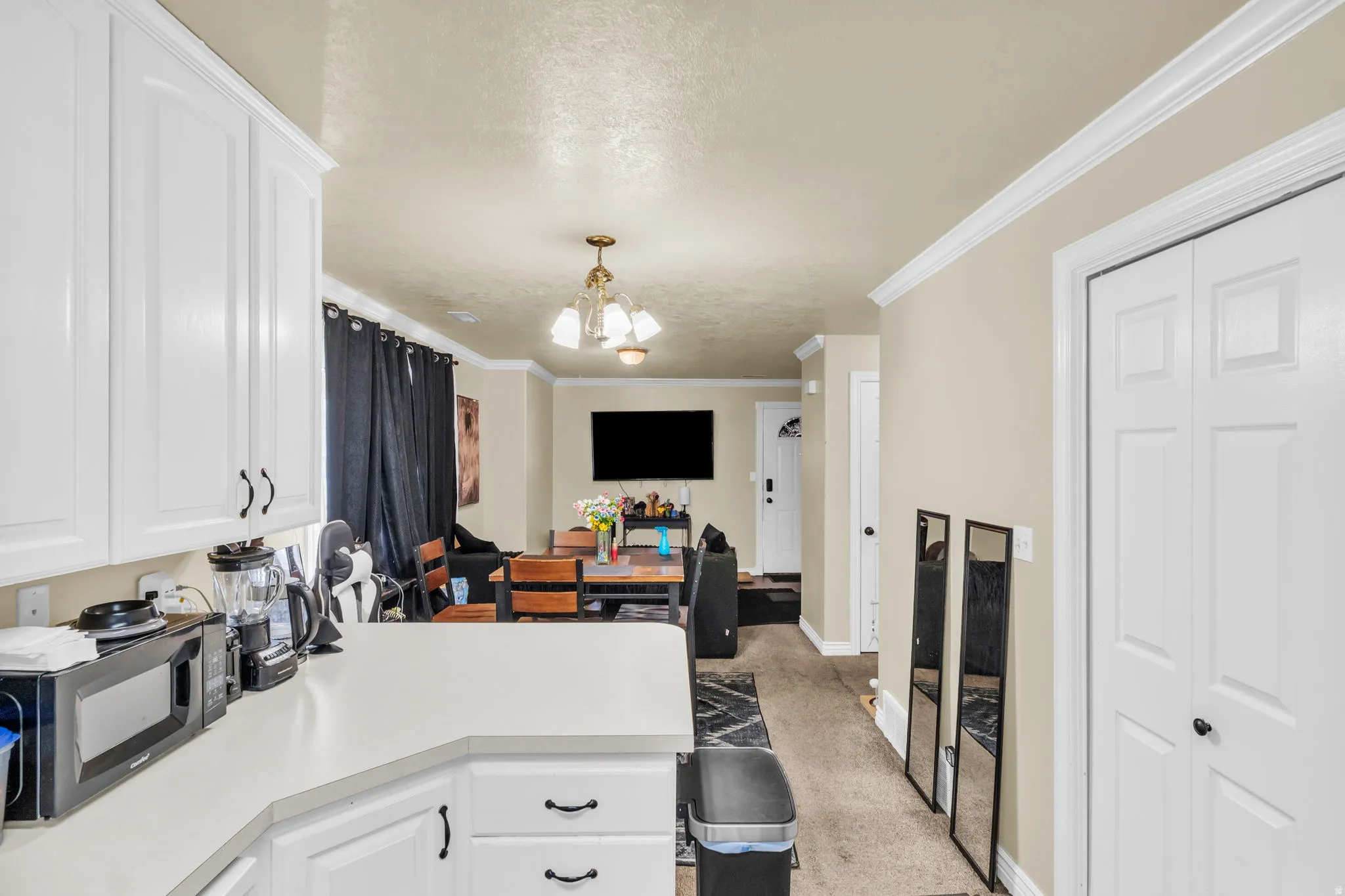 Kitchen counter space featuring white cabinetry, light-toned countertops, and crown molding