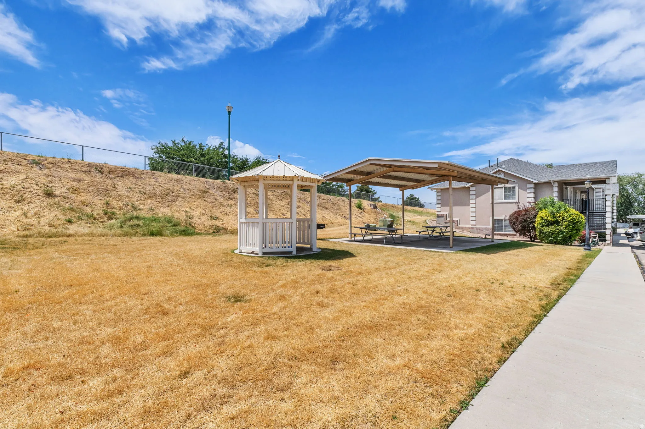 Expansive outdoor space featuring a white gazebo, covered patio area with picnic tables, and a paved walkway