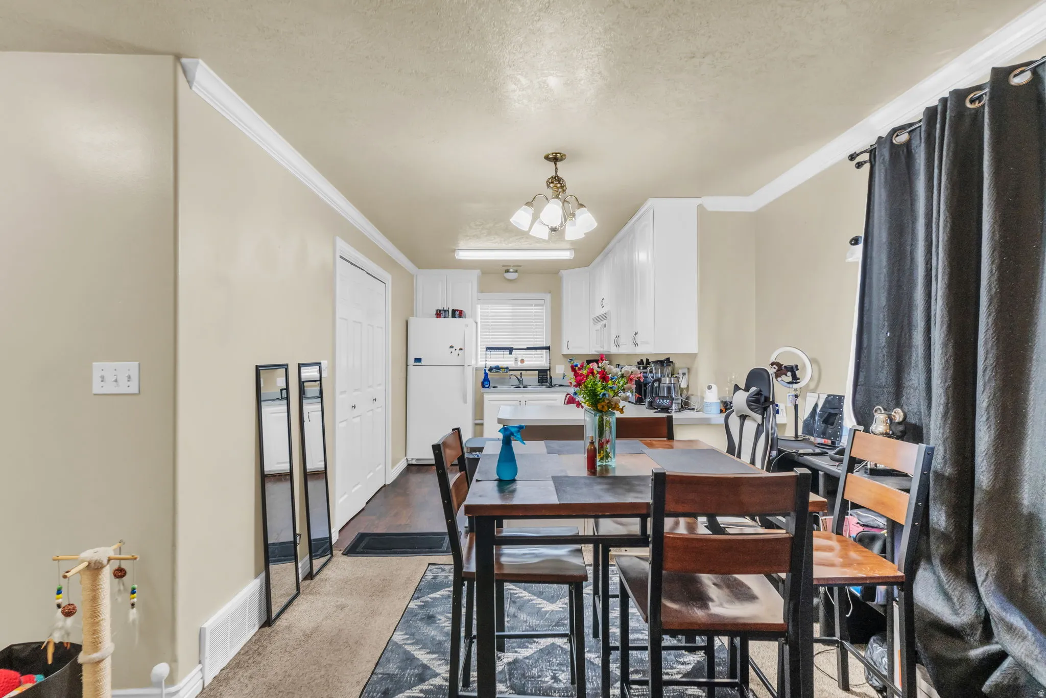 Dining area featuring a rectangular table with seating, white crown molding, and light beige wall paint