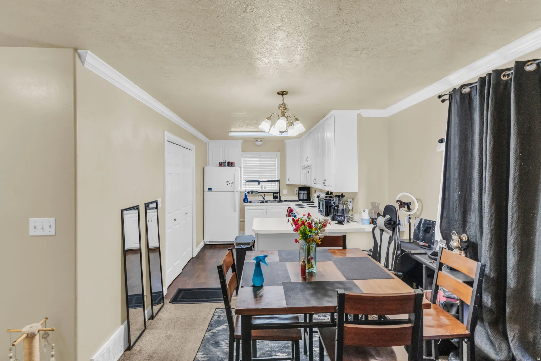 Open-concept kitchen and dining area featuring white cabinetry, a pendant light fixture, and wood-finish flooring
