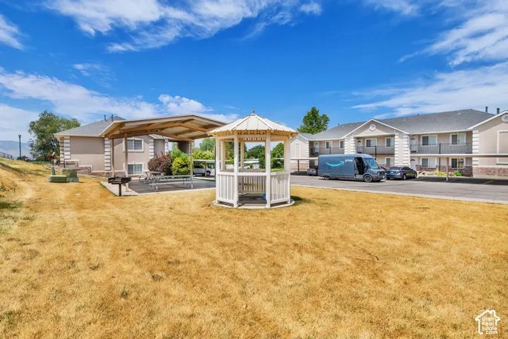 Community grounds featuring a white gazebo, shaded picnic area with seating, and a built-in barbecue grill