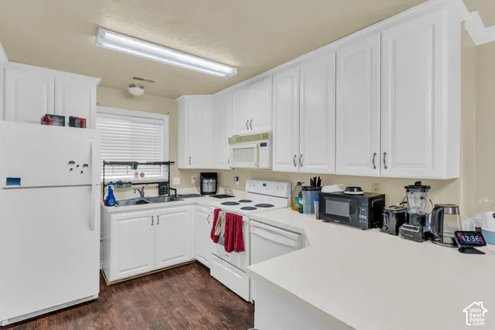 Kitchen featuring abundant white cabinetry, light-toned countertops, and wood-finish flooring