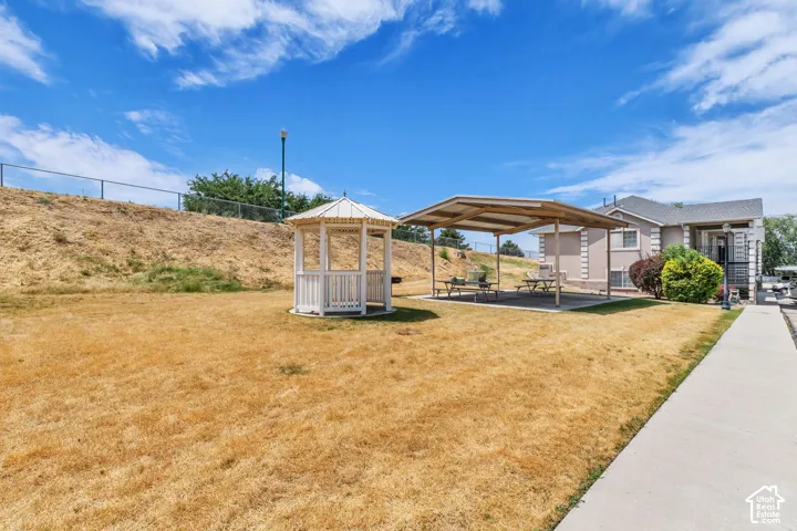 Expansive outdoor space featuring a white gazebo, covered patio area with picnic tables, and a paved walkway