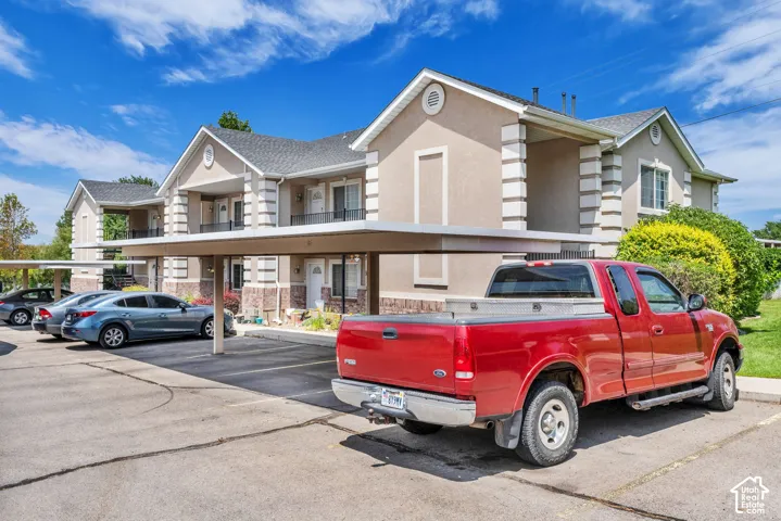 Multi-unit residential buildings featuring stucco and brick veneer exteriors, gabled roofs, and covered parking structures