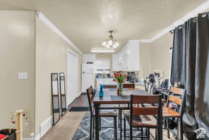 Dining area featuring a rectangular table with seating, white crown molding, and light beige wall paint