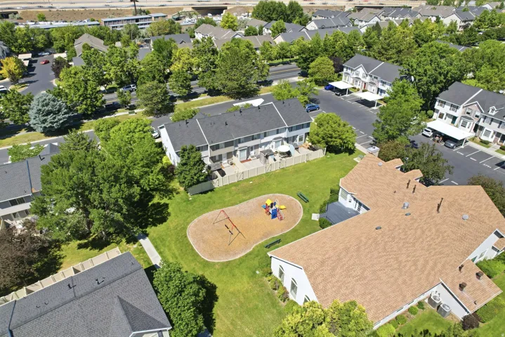 Expansive green space featuring a playground with swing set and slide, surrounded by a manicured lawn and mature trees