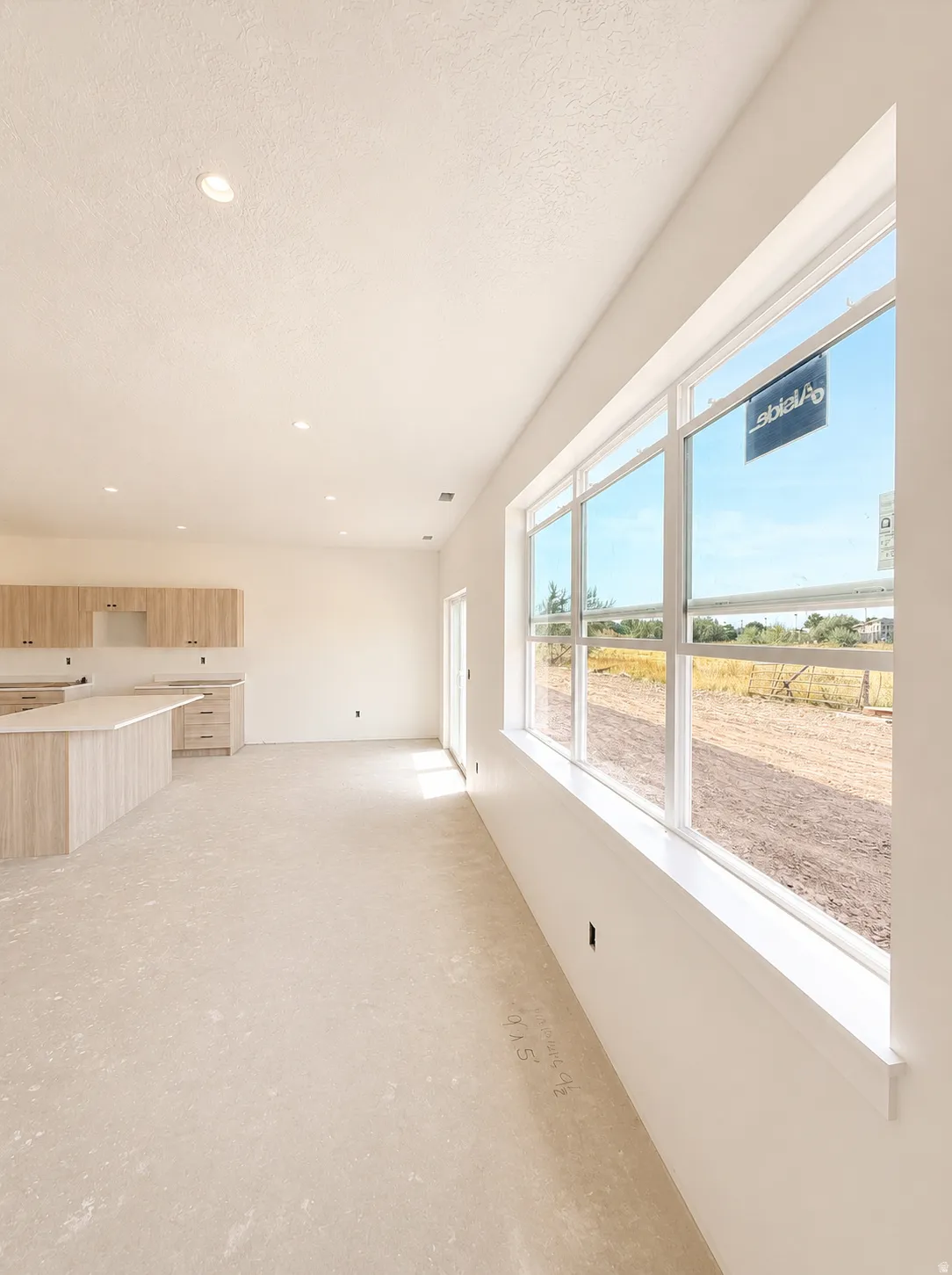 Bright, open-concept living space flooded with natural light through expansive multi-panel windows showcasing scenic countryside vistas