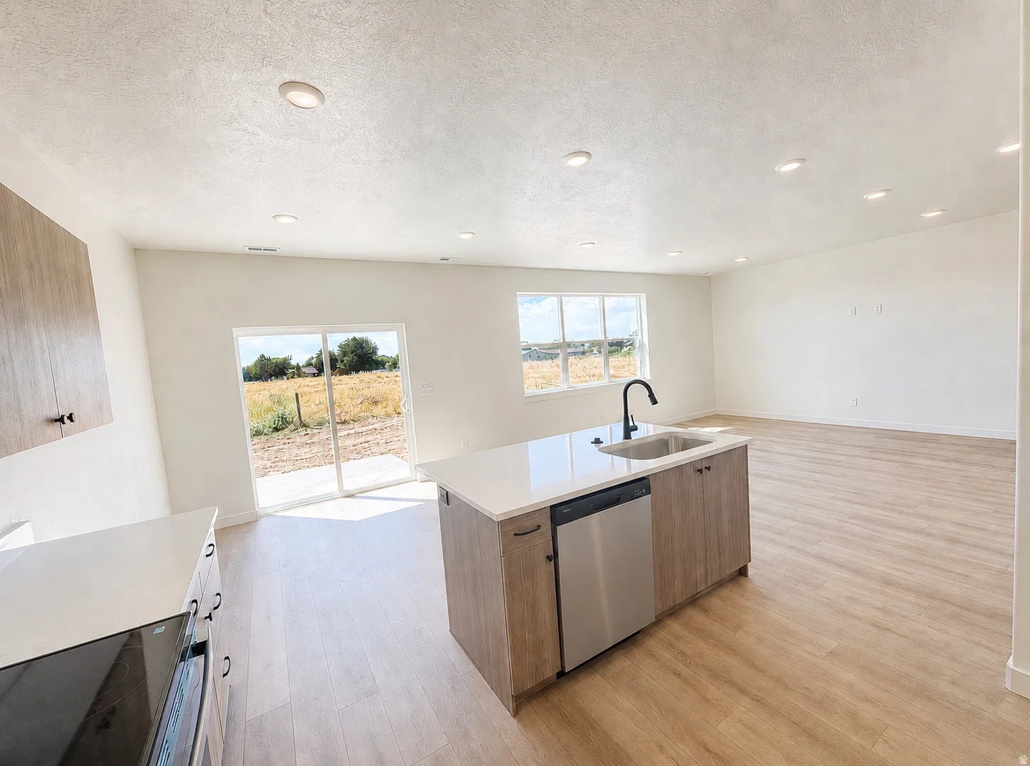 Open-concept living space with wood-finish flooring, recessed lighting, and white walls