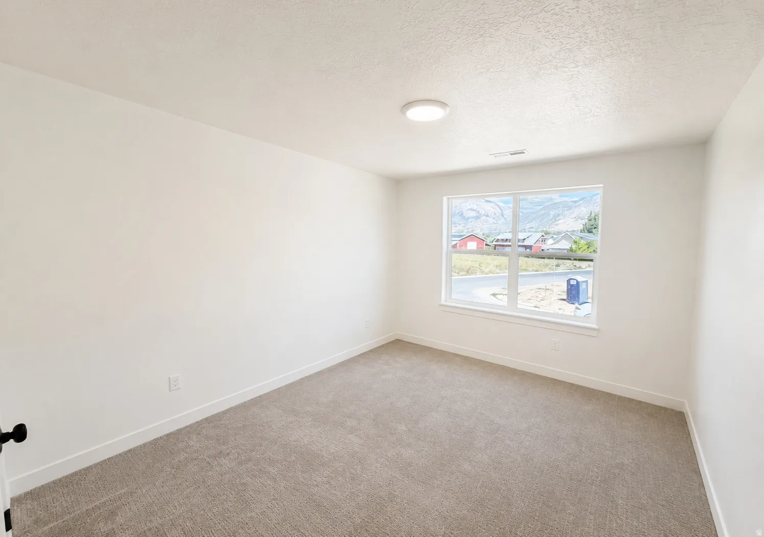 Bright, neutral bedroom featuring neutral carpet flooring, recessed ceiling lighting, and a large window with natural light and exterior views