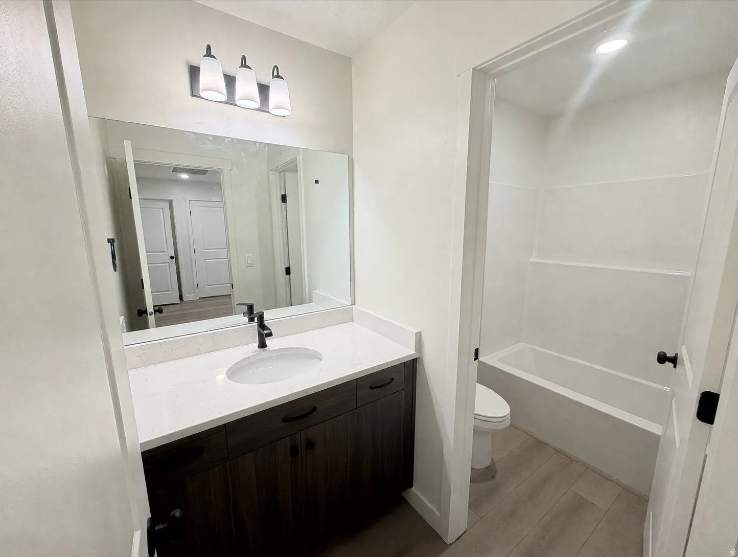Vanity with a light-toned countertop, dark wood-finish cabinetry, and a single basin sink with a matte black faucet