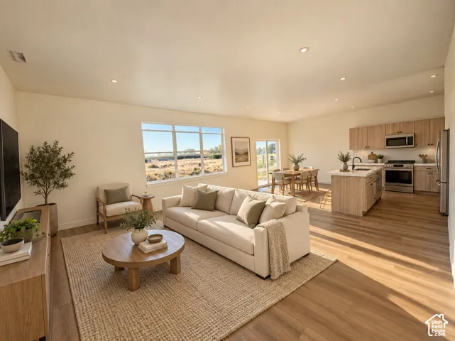 Open-concept living space with recessed lighting, wood-finish flooring, a kitchen island, and a sliding glass door