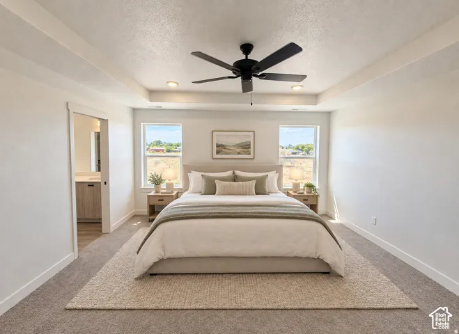 Tray ceiling with recessed lighting and a ceiling fan, two windows, carpeted flooring, and a sliding door