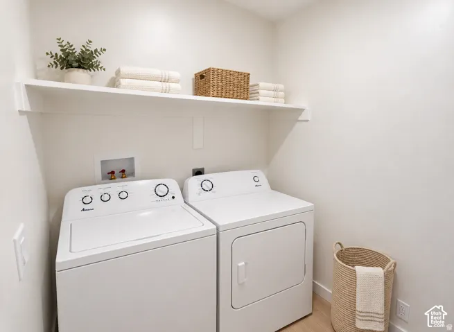 Laundry area with built-in overhead shelving, plumbing hookups, and a light wood-finish flooring