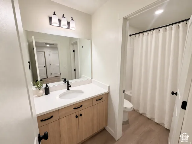 Light-finish wood vanity with black hardware, white countertop, and integrated sink