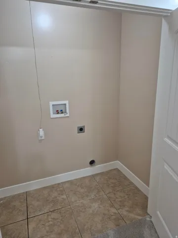 Dedicated laundry area featuring ceramic tile flooring, neutral wall paint, and white baseboards